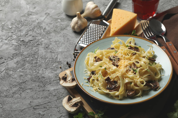 Composizione con piatto di pasta saporita e ingredienti per cucinare su fondo grigio
 - Foto, immagini