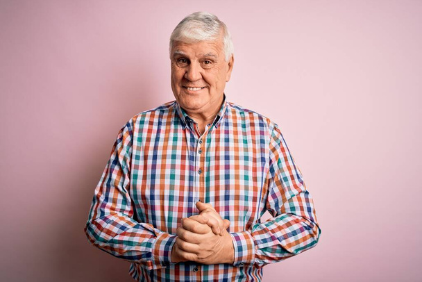 Senior bonito hoary homem vestindo camisa colorida casual sobre fundo rosa isolado com as mãos juntas e dedos cruzados sorrindo relaxado e alegre. Sucesso e otimista
 - Foto, Imagem