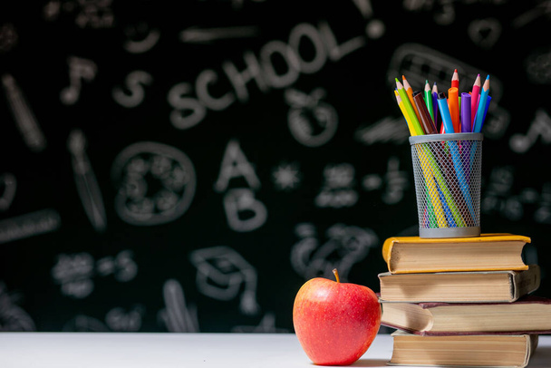 Back to school background with books, pencils and apple on white table - 写真・画像