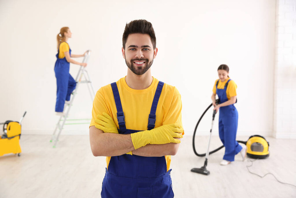 Professional janitor in uniform indoors. Cleaning service - Photo, image