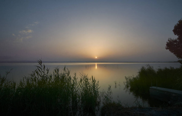 Puesta de sol en el gran lago, de las cañas, verde, colores dorados, aguas tranquilas, reflejos, larga exposición
 - Foto, Imagen