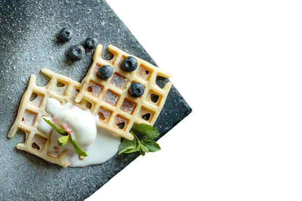 Fresh baked homemade classic Belgian waffles topped with icecream, fresh blueberries and mint isolated on white background, top down view. Savory waffles. Breakfast concept. - Foto, Bild