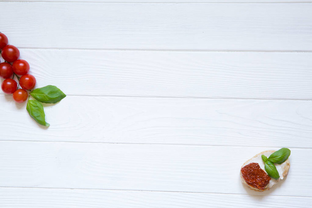 Bruschetta with dry tomatos, goat white cheese and basil on the white rustic wooden background. Italian cuisine, top view. Copy space.  - Photo, Image