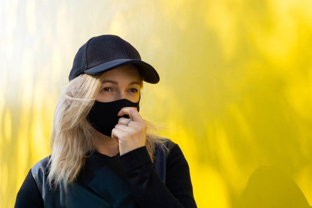 Woman with black mask on the yellow background during epidemic infection. - Foto, afbeelding