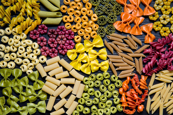 Different kinds of pasta on black wooden background, italian cuisine.  - 写真・画像