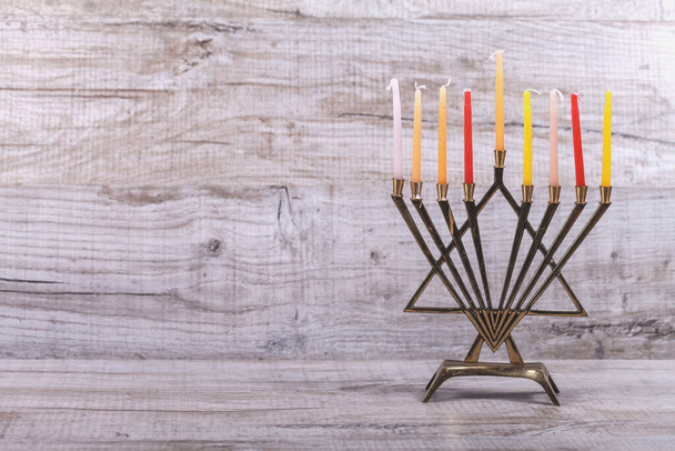 Еврейский праздник Ханука. Менора со свечами на светлом, деревянном фоне. Концепция еврейского праздника Хануки. Вид спереди
 - Фото, изображение