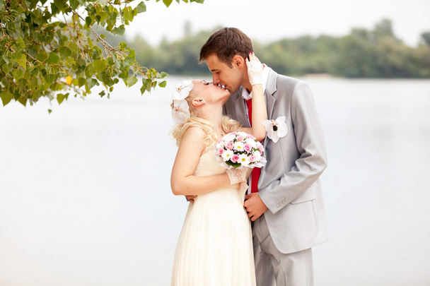 Just married couple kissing passionately on riverbank - Photo, Image