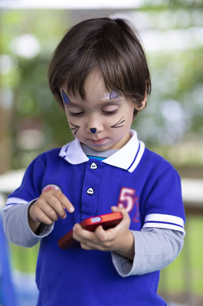 Lovely Boy with Painted Face, Playing on Mobile Phone - Photo, Image