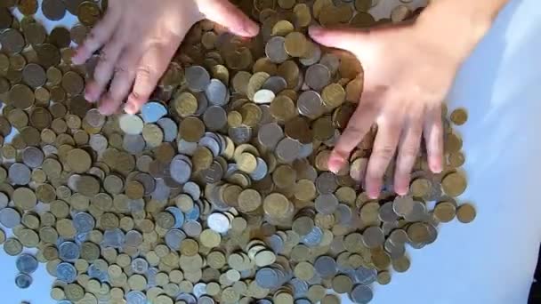 Persona dos manos rastrillos monedas en la mesa y derrama derrames de puñado a la superficie - Metraje, vídeo