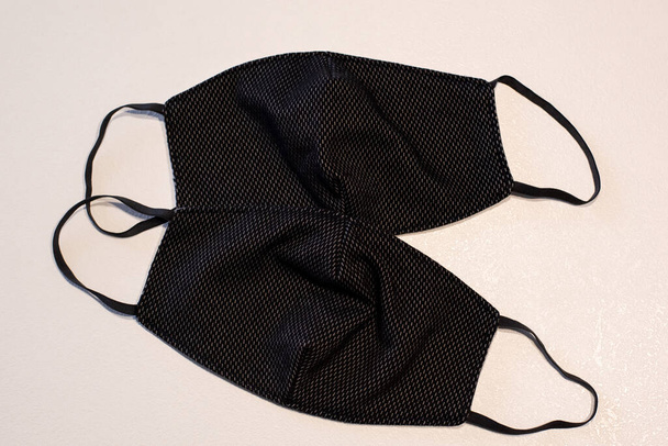 Máscara facial negra hecha a mano. Máscaras de tela negra sobre un fondo blanco. Protección contra virus
 - Foto, Imagen