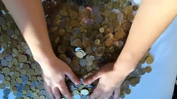 Persoon twee handen harkt munten op tafel en giet morst van handvol naar oppervlakte - Video