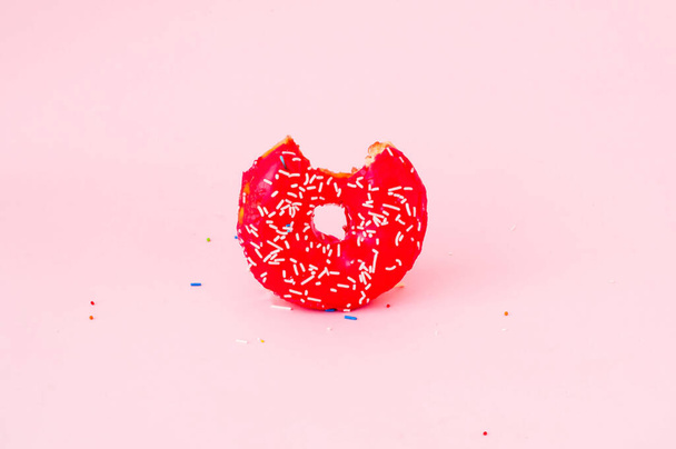 Rosquilla roja con coloridas salpicaduras sobre fondo rosa. Concepto del Día Nacional de Donuts o Donuts. Espacio de copia, primer plano
 - Foto, imagen