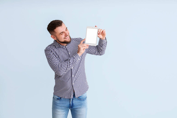 Young man with tablet computer on color background - Photo, image
