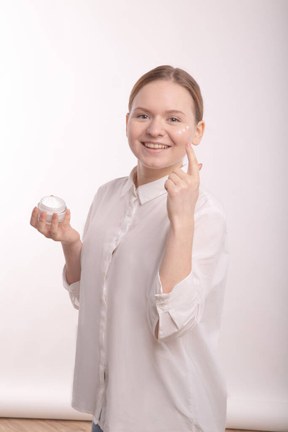 Applying a natural cream on the face. Young girl with natural beauty. - Foto, Bild