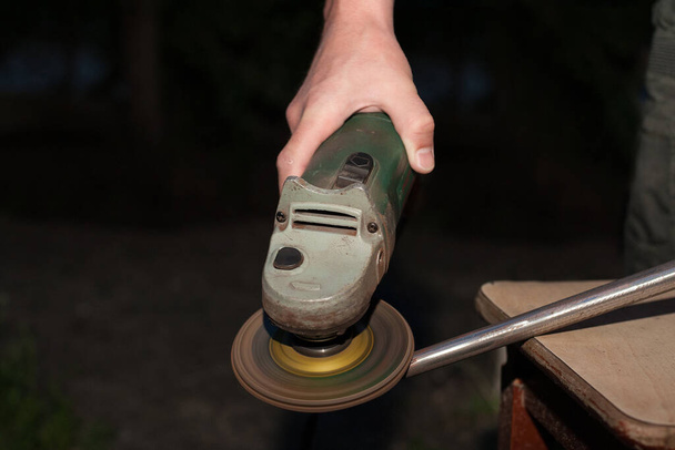 A man works with a blacksmith's disc grinder. Close-up of the abrasive disc cutter used. The hands of a skilled worker operate the power tool - Photo, Image