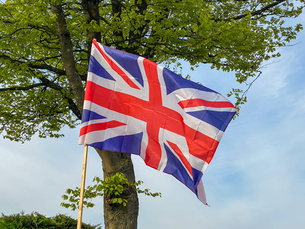 Union Jack flag flying on a wooden pole in a garden - Photo, Image
