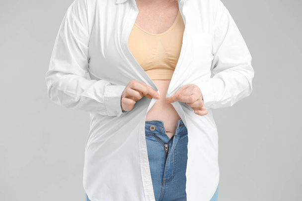 Mujer con sobrepeso sobre fondo gris, primer plano
 - Foto, imagen