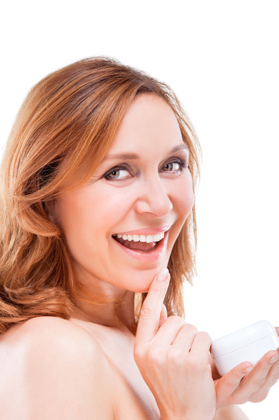 Beautiful adult woman applying cream on face. - Photo, image