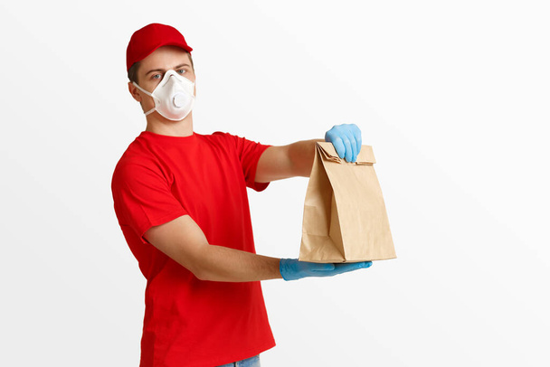 Fast delivery at home. Courier in medical mask and gloves holds package - Photo, Image