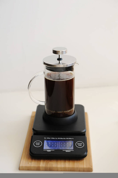 Brewing coffee in french press. Plunger down. On black electronic timer scales. - Photo, Image