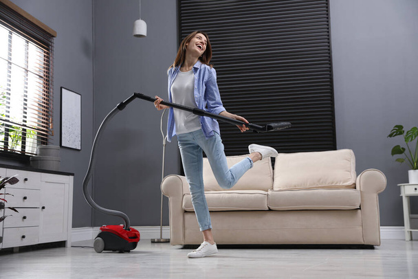 Young woman having fun while vacuuming at home - 写真・画像