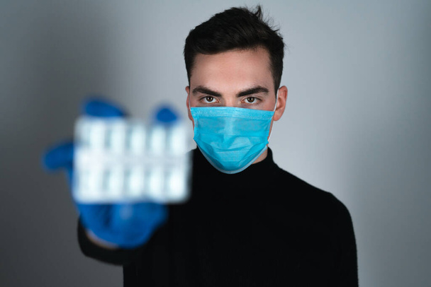 Lääketieteellinen naamio ja käsineet pitää läpipainopakkaus pillereitä
  - Valokuva, kuva