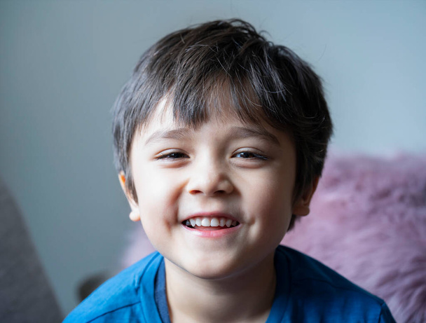 Zdjęcie zdrowego dziecka, Portret szczęśliwego dziecka patrzącego w kamerę z uśmiechniętą twarzą, szczery strzelił do słodkiego chłopca relaksującego się w domu. Pozytywna koncepcja dzieci - Zdjęcie, obraz