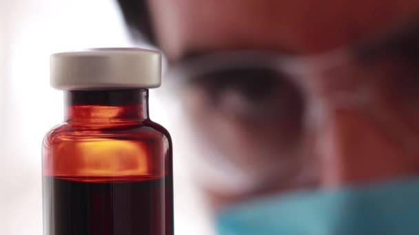 Pesquisador farmacêutico observando cuidadosamente um frasco de vidro marrom
 - Filmagem, Vídeo