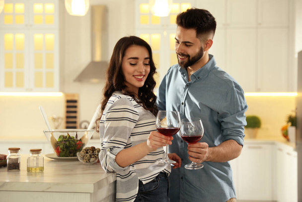 Lovely young couple drinking wine while cooking together at kitchen - Foto, imagen