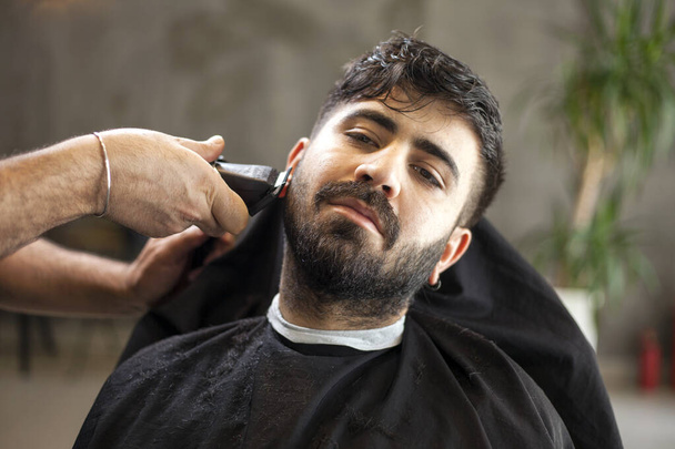  Peluquero masculino sirviendo cliente, haciendo corte de pelo usando máquina y peine
. - Foto, Imagen