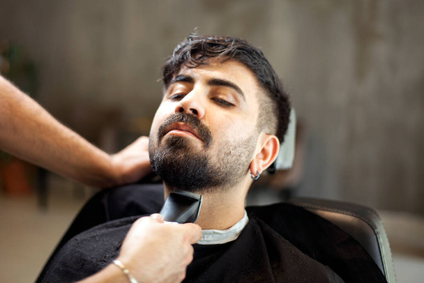  Homme coiffeur servant client, faire la coupe de cheveux à l'aide de la machine et peigne
. - Photo, image