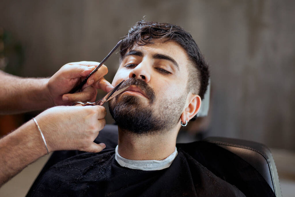  男性のヘアスタイリストは、クライアントにサービスを提供し、マシンと櫛を使用してヘアカットを作る. - 写真・画像
