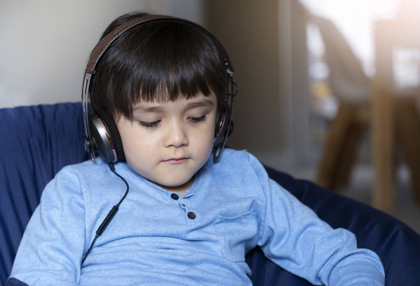 Portrait cute little boy wearing head phone listing music or learning online, Happy kid relaxing at home, Positive child stay at home while covid 19 lock down. Home schooling, E-learning education  - Photo, Image