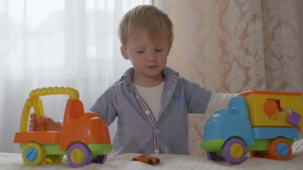 söpö onnellinen iloinen miespuolinen lapsi, jolla on hyvä hermosto ja hyvä terveys, hauskaa leikkiä muovisilla värillisillä leluilla
 - Materiaali, video