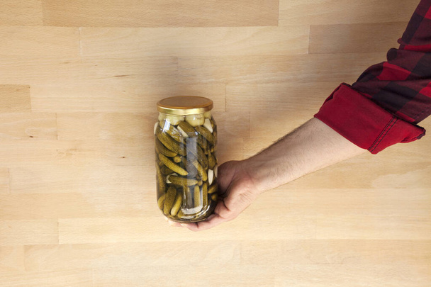 Person mit einem Glas Essiggurken Hausgemachte eingelegte Gurken in einem Glas.  - Foto, Bild