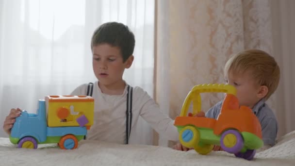 dzieci związek, słodkie chłopcy kochający krewnych grać razem z plastikowymi kolorowymi samochodami zabawki razem - Materiał filmowy, wideo