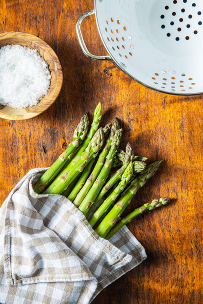 Fresh green asparagus. Healthy seasonal vegetable on wooden table. Top view. - Fotó, kép