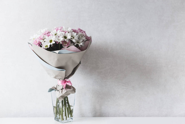 Букет з біло-рожевих хризантем у скляній вазі на столі
. - Фото, зображення