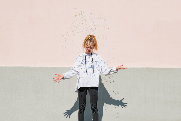 A young girl throws white petals against the background of a house - Foto, Imagem