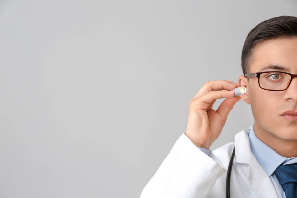 Männlicher Arzt mit Taschenlampe auf grauem Hintergrund - Foto, Bild