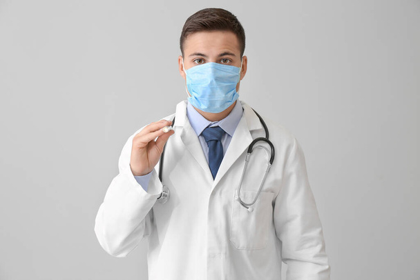 Αρσενικός γιατρός με φακό σε γκρι φόντο - Φωτογραφία, εικόνα