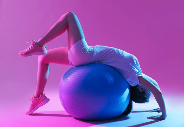 Спортивная молодая женщина тренируется на цветном фоне
 - Фото, изображение