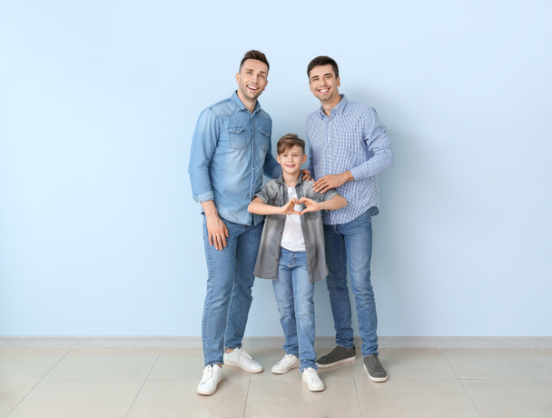 szczęśliwy gej para z adoptowany dziecko blisko kolor ściana - Zdjęcie, obraz