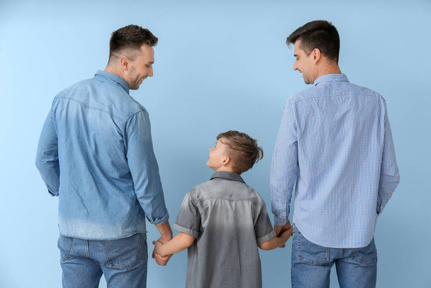 Happy gay couple with adopted child on color background - Photo, Image
