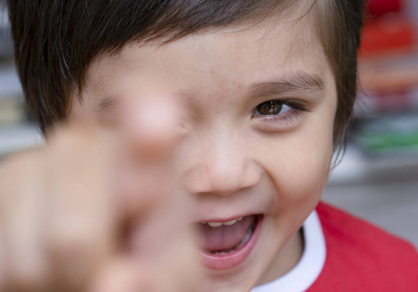 Selective focus little boy with smiling face pointing finger at camera, Candid short of kid primary school boy pointing at you with his finger, Spoiled children concept - Photo, Image
