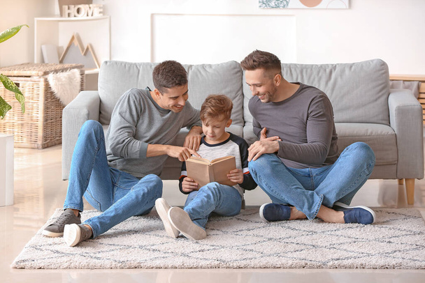 Happy gay couple with adopted child reading book at home - Foto, Imagem