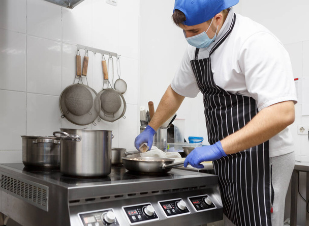 Man in protective mask and gloves frying tasty food - Foto, Imagen