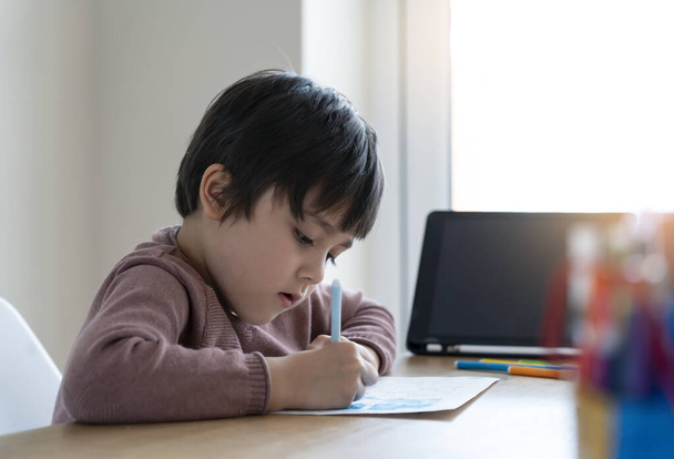 Дитяча самоізоляція, використовуючи планшет для домашнього завдання, Дитина використовує цифровий планшет для пошуку інформації в Інтернеті під час ковадла 19 блокування вниз, домашнє навчання, соціальна відстань, онлайн-освіта
 - Фото, зображення