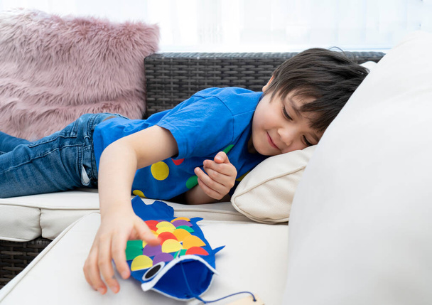 Korkea avain onnellinen lapsi jäädä kotiin makaa sohvalla leikkii Koinobori (Carp serpentiinit), Lapsipoika tekee japanilainen kala leija aurinkoisena päivänä kesällä, Etäopetus tai kotiopetuksessa, Lasten päivä
  - Valokuva, kuva