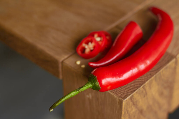 Close up de pimentas vermelhas picantes fatiadas na mesa de madeira, foco seletivo
 - Foto, Imagem